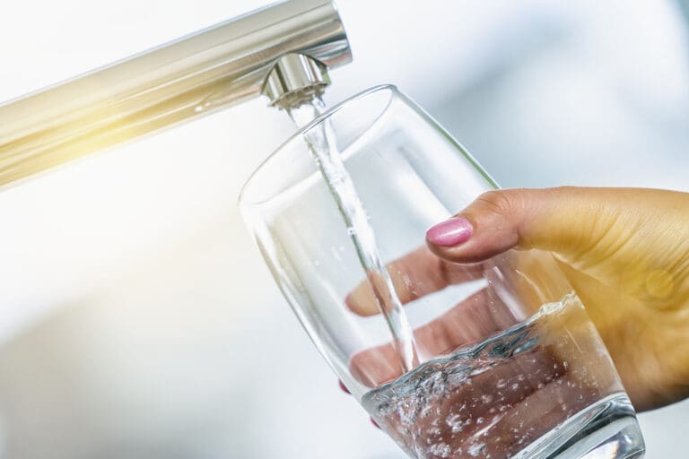 Woman hand's filling the glass of water.